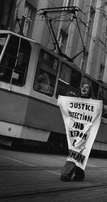 A demonstrator marches past a Sofia tram carrying a hand-painted banner demanding justice, protection and freedom for Abdulrahman